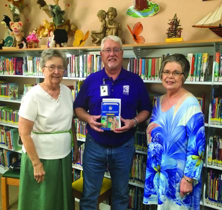 Clifton’s Nellie Pederson Civic Library Director Lewis Stansell accepts a donated copy of Davy Crockett: Young Rifleman from Clifton Study Guild members Shirley Dahl and Sue Fielden. Courtesy Photo