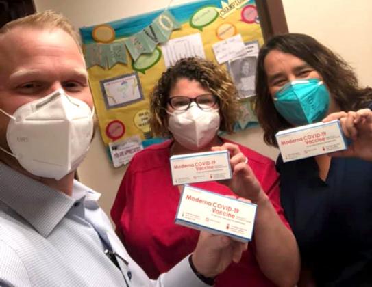 CEO and President Adam Willmann, Clifton Clinic Manager Carrie Oberhaus and Nurse Mandy Ringo break out the first shipment of the COVID-19 vaccine Wednesday.