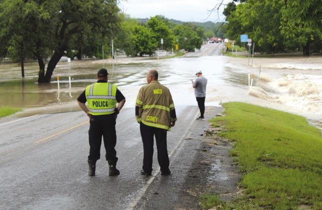 Nathan Diebenow | The Clifton Record In the distance, first responders wait for a heliocopter to pick them up on FM 219 between two bridges outside Clifton City Park flooded out by the Bosque River on Sunday morning, May 5.