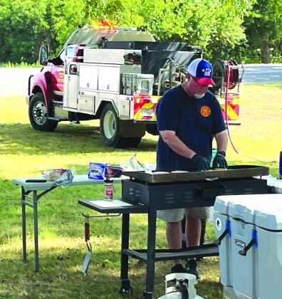 Meridian Volunteer Fire Department Chief Kevin Brister grills hamburgers for guests during the MVFD’s fundraiser at Meridian Park on Saturday, July 15. Nathan Diebenow | Meridian Tribune