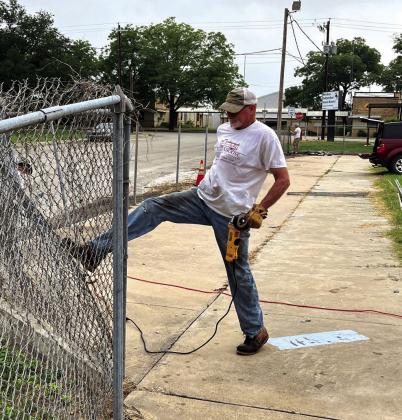 Meridian Grassroots volunteer Paul Hardcastle kicks a section of fence down around the City of Meridian’s former swimming pool on Saturday morning, June 17. Nathan Diebenow | Meridian Tribune