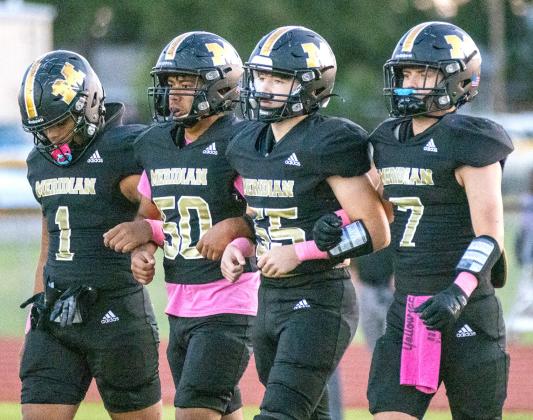 Yellowjacket junior quarterback Matty Jones takes off running against Hubbard (far left); Meridian senior arm-in-arm for coin toss (above). Photos by Wendy Orozco courtesy of Brett Voss’ The Sports Buzz