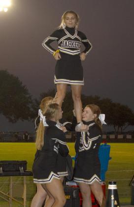 Right, Saedie Settles stands at the top of a pyramid as the Yellow Jacket cheerleaders perform for the fans.