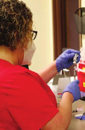 Bottom, Carrie Oberhaus prepares a dose of the COVID-19 vaccine to be delivered at Goodall-Witcher last Wednesday.